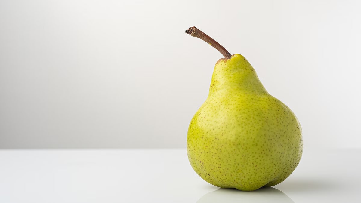 Close-up of a ripe and fresh green pear on a clean white background, ideal for healthy eating concepts.